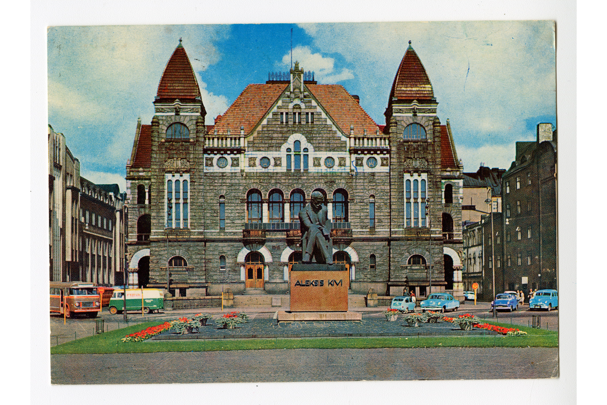 Vaakatasoinen postikortti, jossa on kuva Aleksis Kiven patsaasta taustallaan Kansallisteatteri.