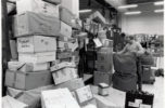 Kasoittain isoja postipaketteja hallin seinustoilla työntekijän avatessa postisäkkiä.
