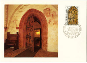 Hollolan kirkon asehuoneen ovi kuvattuna postikortissa ja -merkissä.